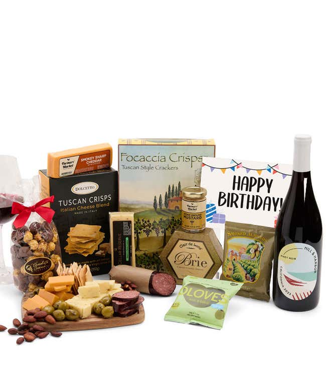 A charcuterie gift set with Tuscan crisps, focaccia crackers, 3 cheeses, summer sausage, olives, mustard, smoked almonds, chocolate-covered popcorn, and a birthday card.