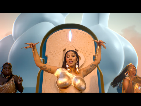 screenshot from lizzo and cardi b rumors music video where cardi b wears golden breastplate with her hands raised
